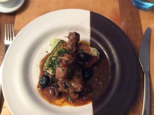 Grilled pork chops stacked on top of a portion of pommel boulangère.  Garnished with fresh green herbs.